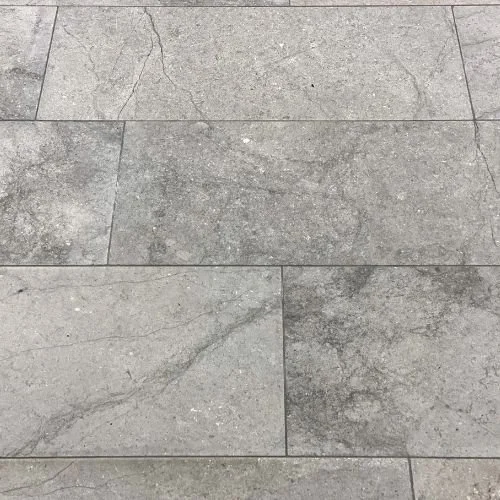 Close-up of gray stone floor tiles with natural veining and cracks.