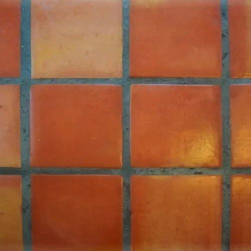 Close-up of orange ceramic tiles with gray grout lines.