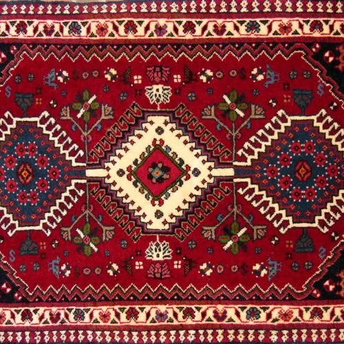 A traditional Persian-style rug with a red background, geometric patterns, floral motifs, and intricate borders.