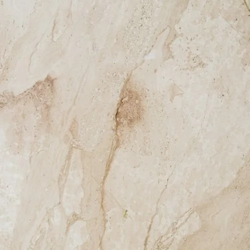 Close-up of a beige marble surface with natural veining and texture.