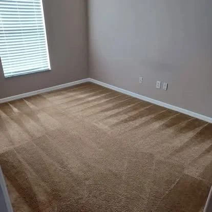 Empty beige carpeted room with a window, baseboards, and two electrical outlets.