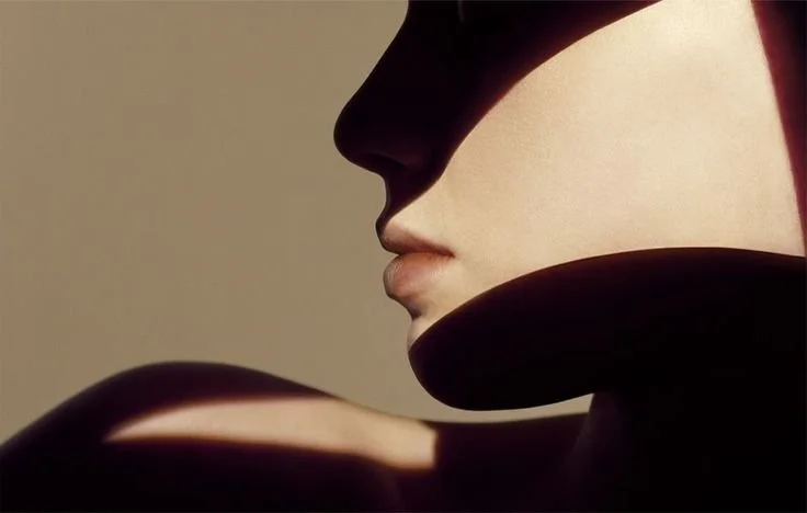 Close-up profile of a person's face, with shadows highlighting their nose, lips, and chin.