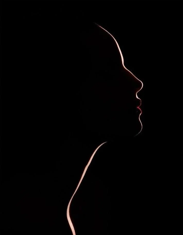 Silhouette of a person's profile outlined by light against a black background.