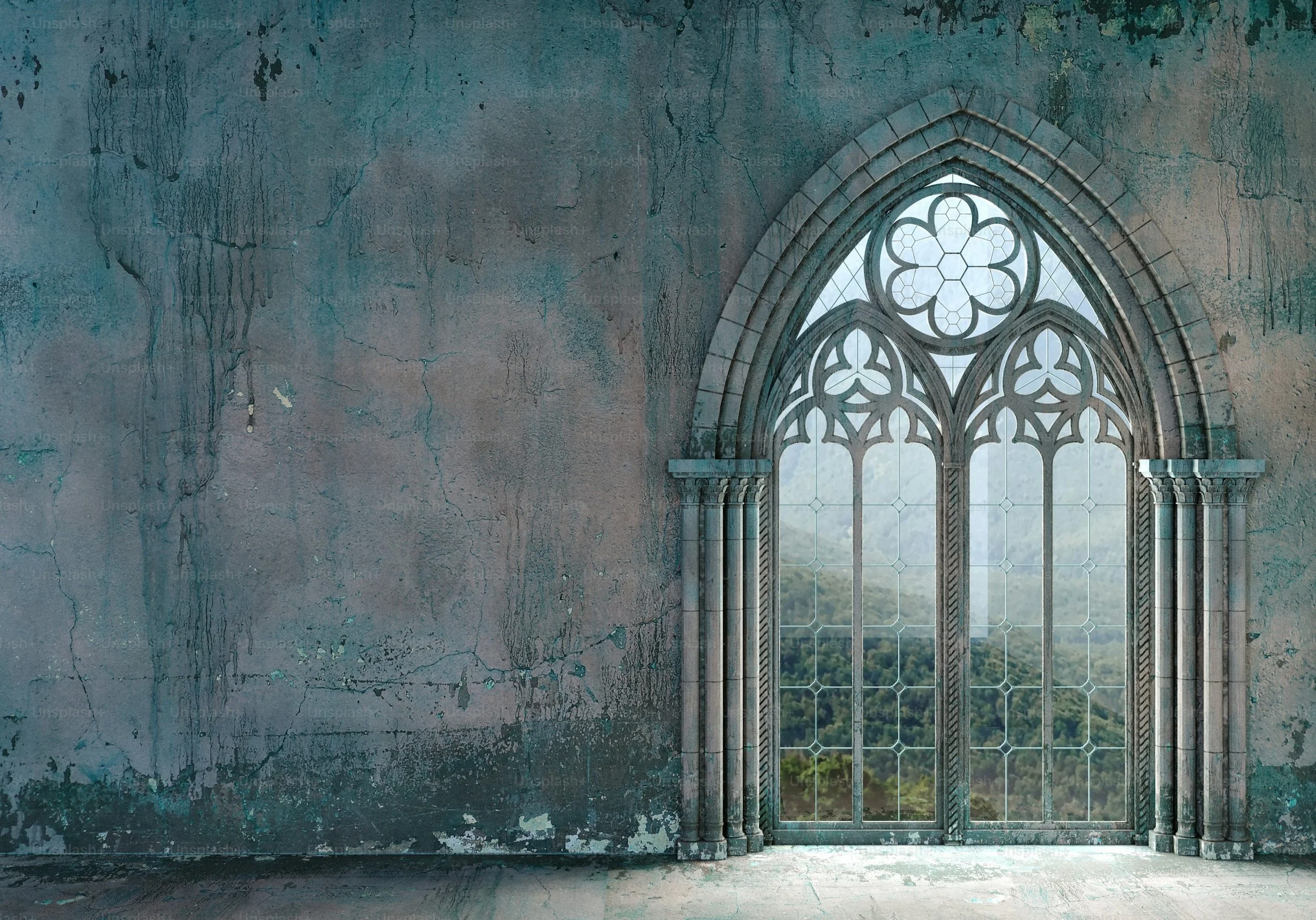 An old stained concrete wall with a Gothic-style arched window featuring intricate stone tracery and clear glass, revealing a lush green landscape outdoors.