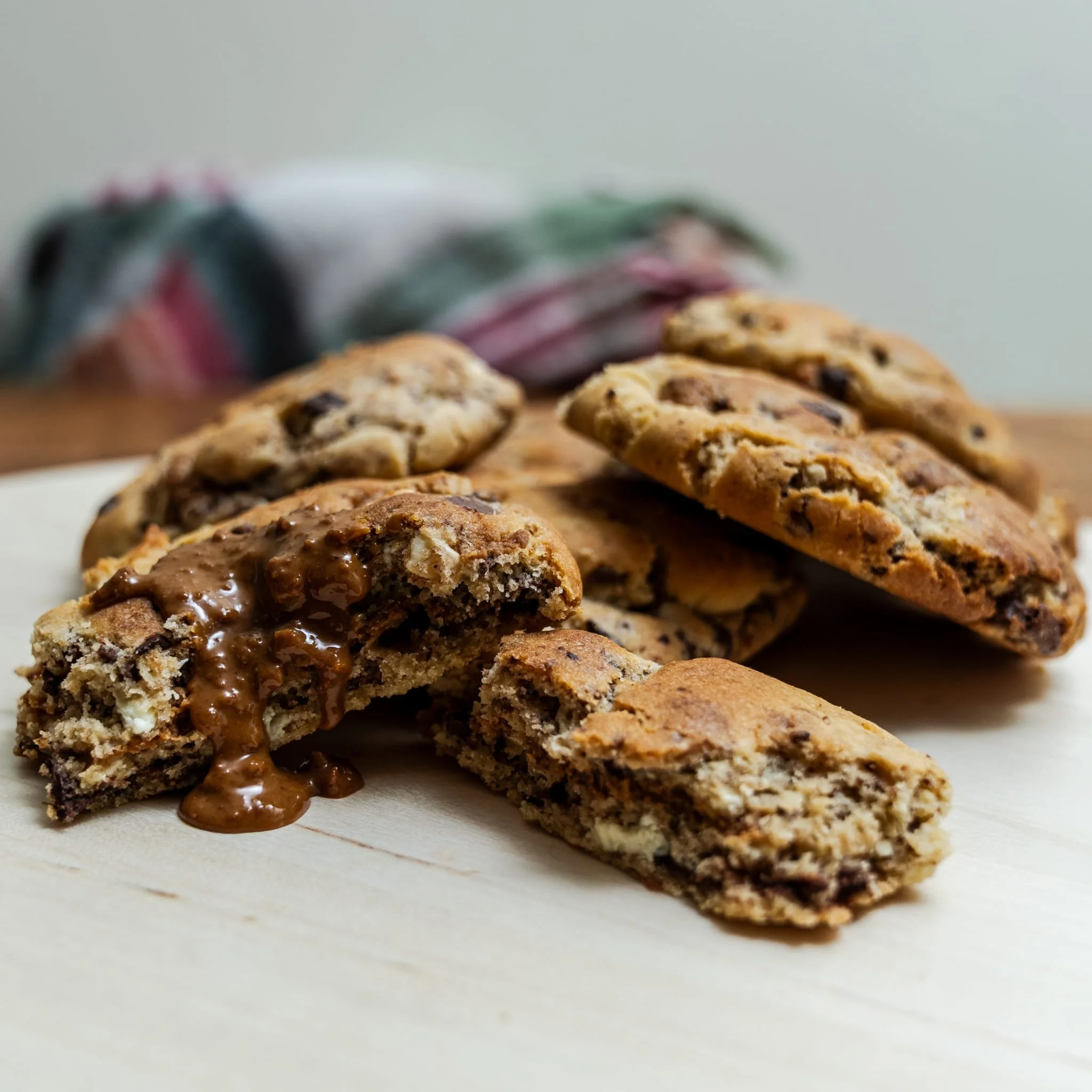 Close-up of chocolate chip cookies with melted chocolate on a white surface.