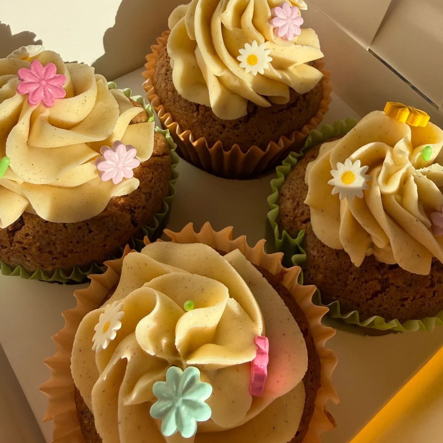 Decorated cupcakes with swirl frosting, colorful edible flowers, and decorative sugar accents.