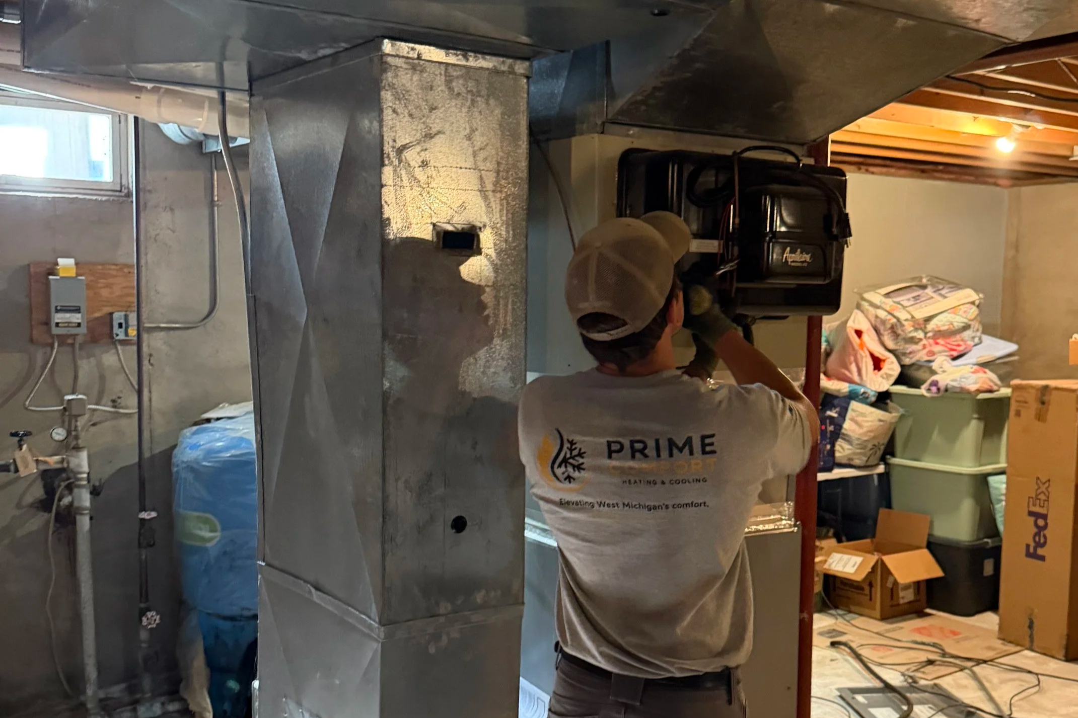 A technician from Prime Comfort is repairing an outdoor Goodman air conditioning unit, with tools and a service bag nearby, outside a residential house.