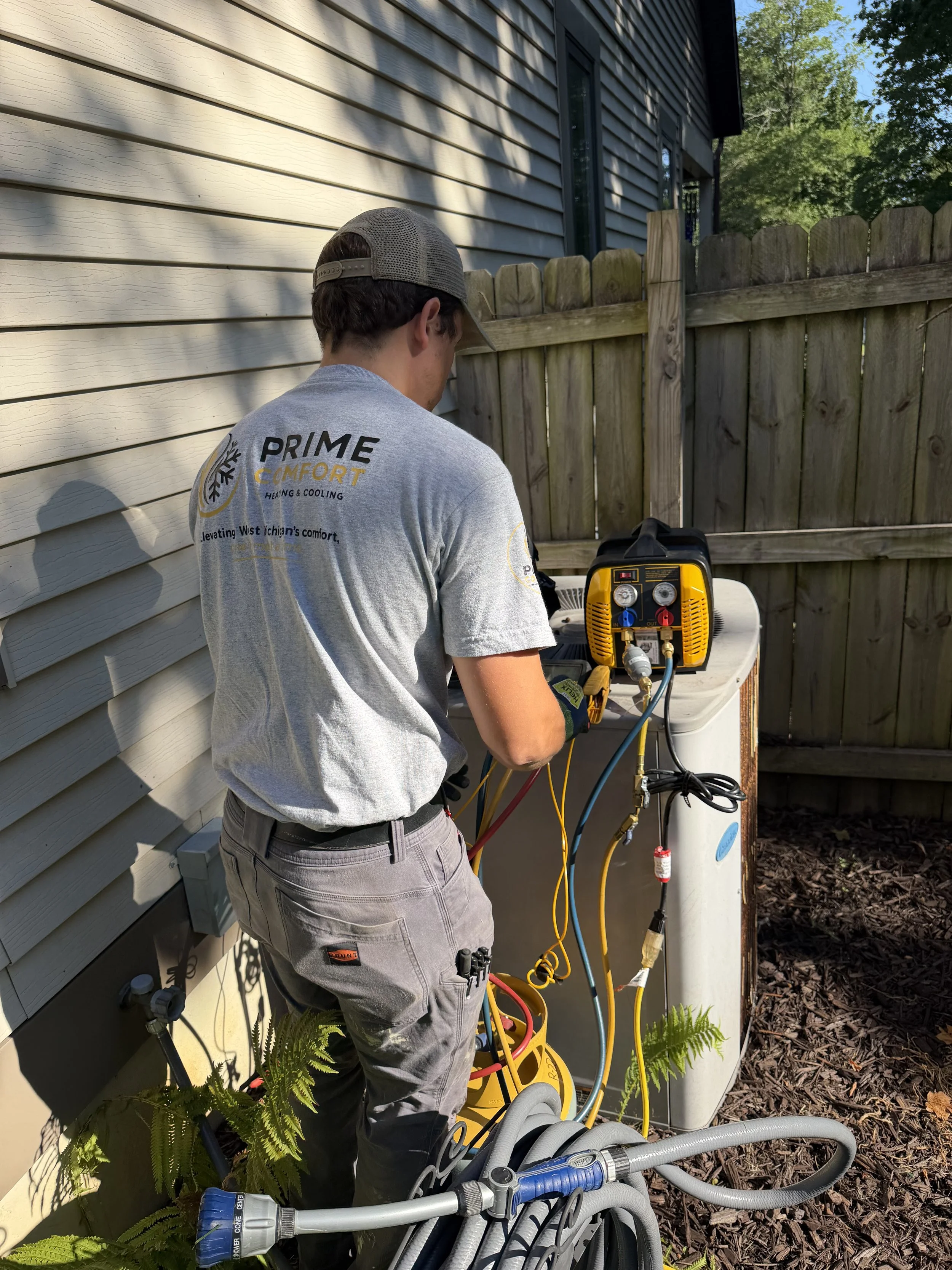 Technician working on a heat pump outdoor unit in Byron Center