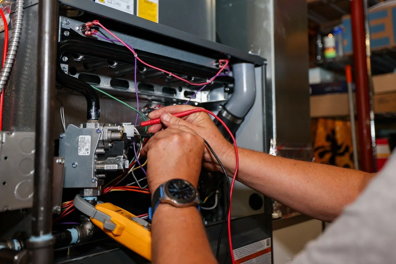 Prime Comfort technician testing furnace electrical components with a multimeter during a Grand Rapids furnace repair