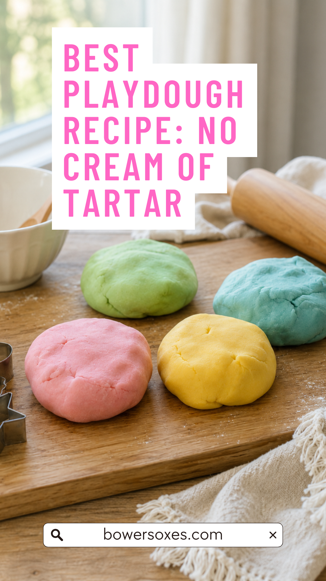 4 colors of home made playdough on a table with a rolling pin, towel and bowl