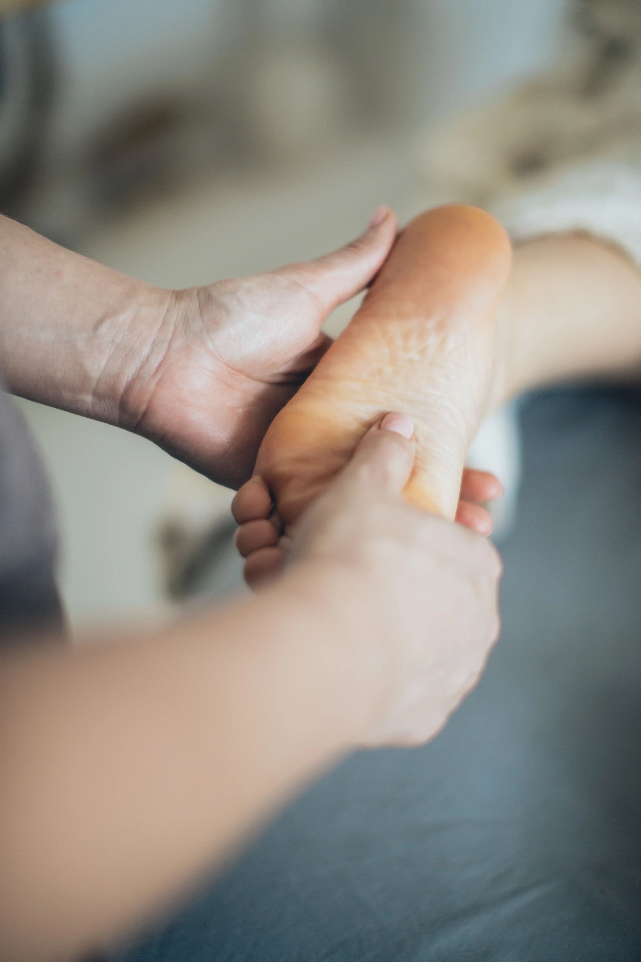 A person holding a sandal with a bare foot, seen from the side, in a close-up shot.
