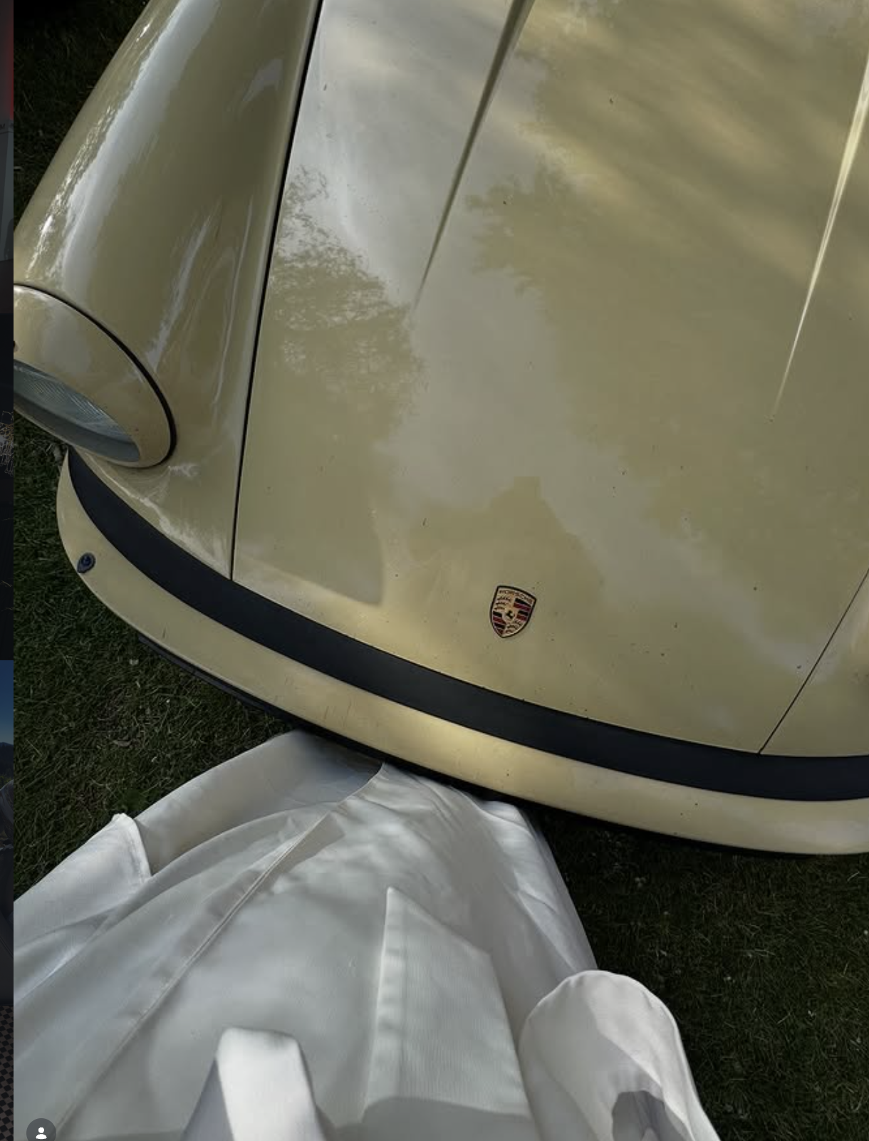 Close-up of the front of a vintage yellow Porsche car with the Porsche crest visible on the hood, with a white cloth partially covering the bottom of the image.