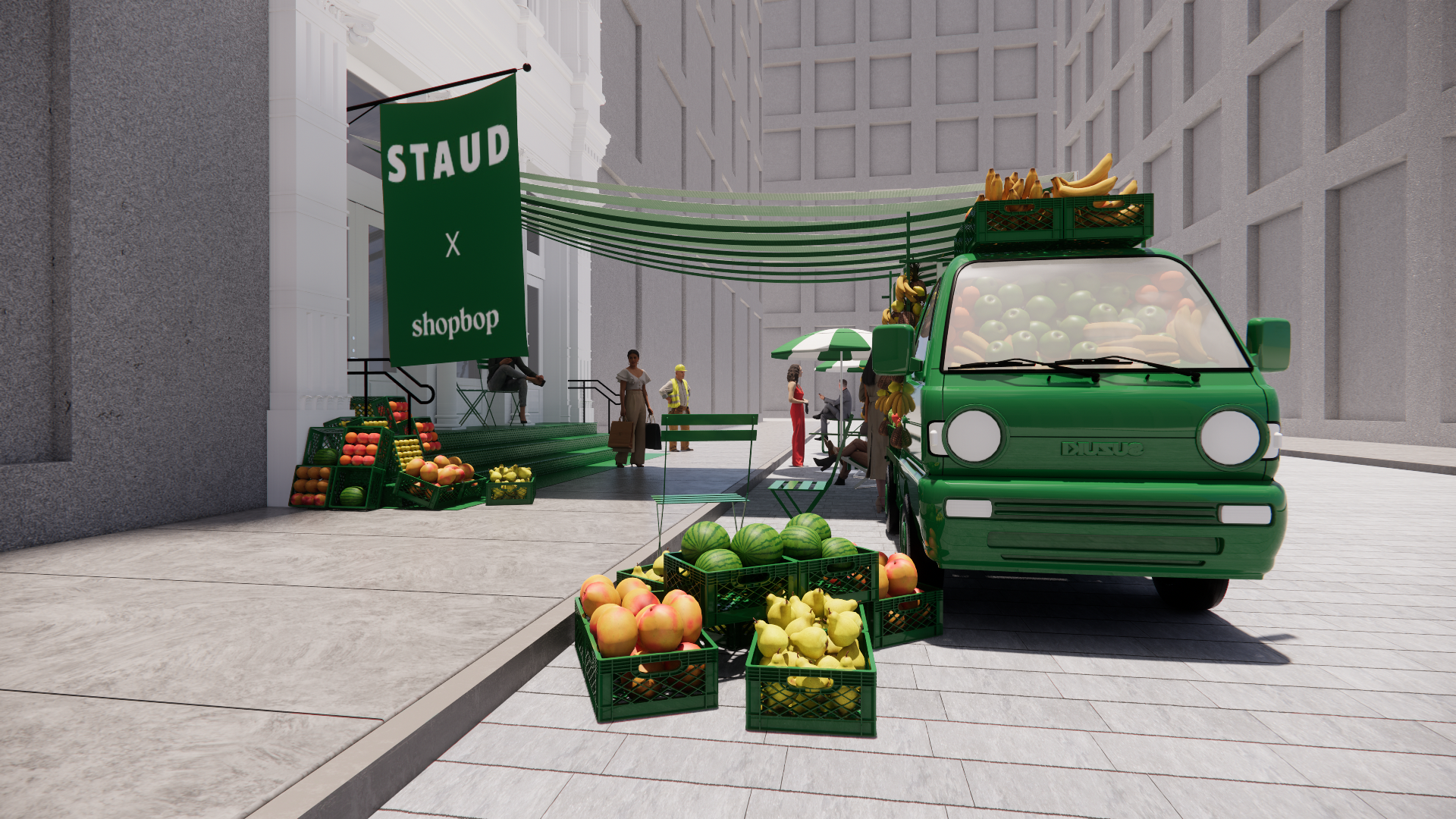 Green food truck selling fruits, including bananas, apples, and watermelons, parked on the street near a small outdoor market with crates of produce, with shoppers and vendors around.