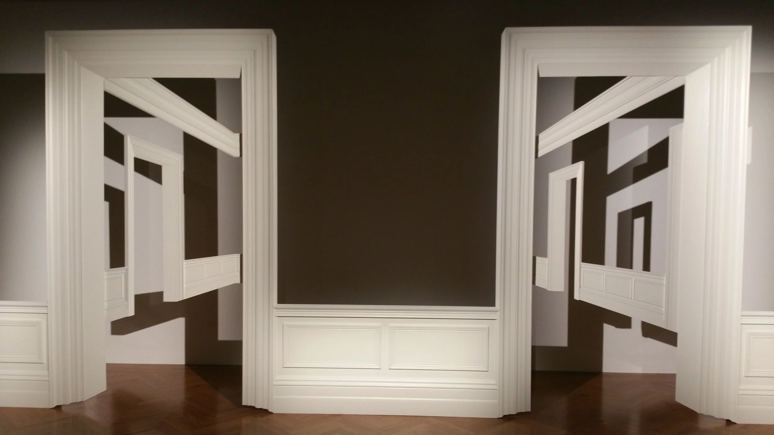 Installations of white door frames and moldings arranged on a wall.