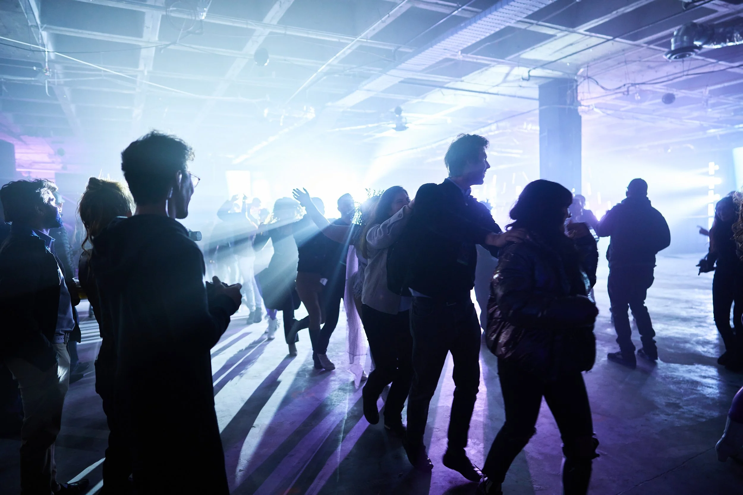 People dancing and socializing at a vibrant indoor nightclub with colorful lights and a lively atmosphere.