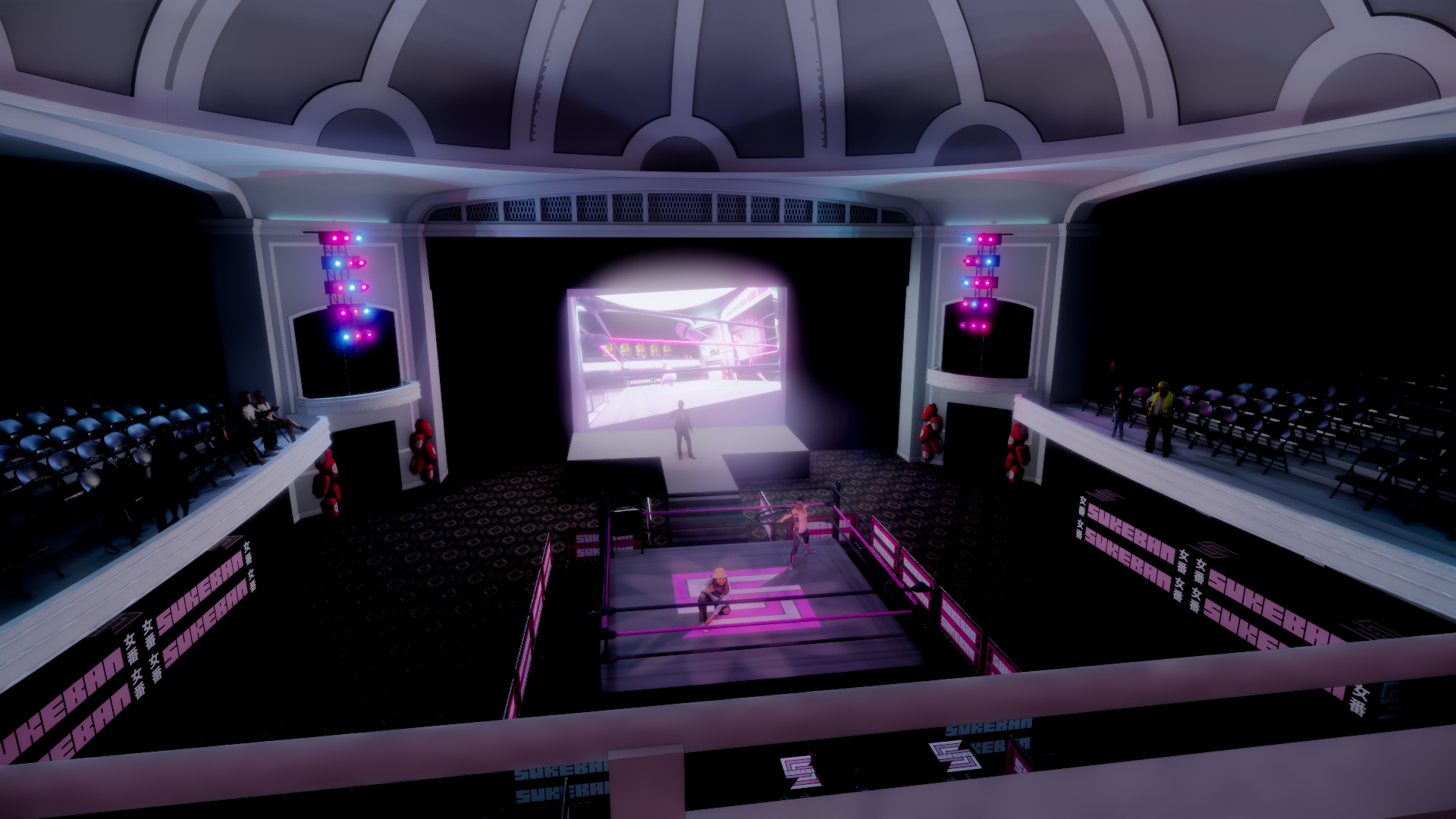 An indoor wrestling arena with a wrestling ring in the center and a large screen behind it displaying a match. Audience seats are on the left and right sides, with some spectators watching. The arena is decorated with pink and blue lighting, and ther