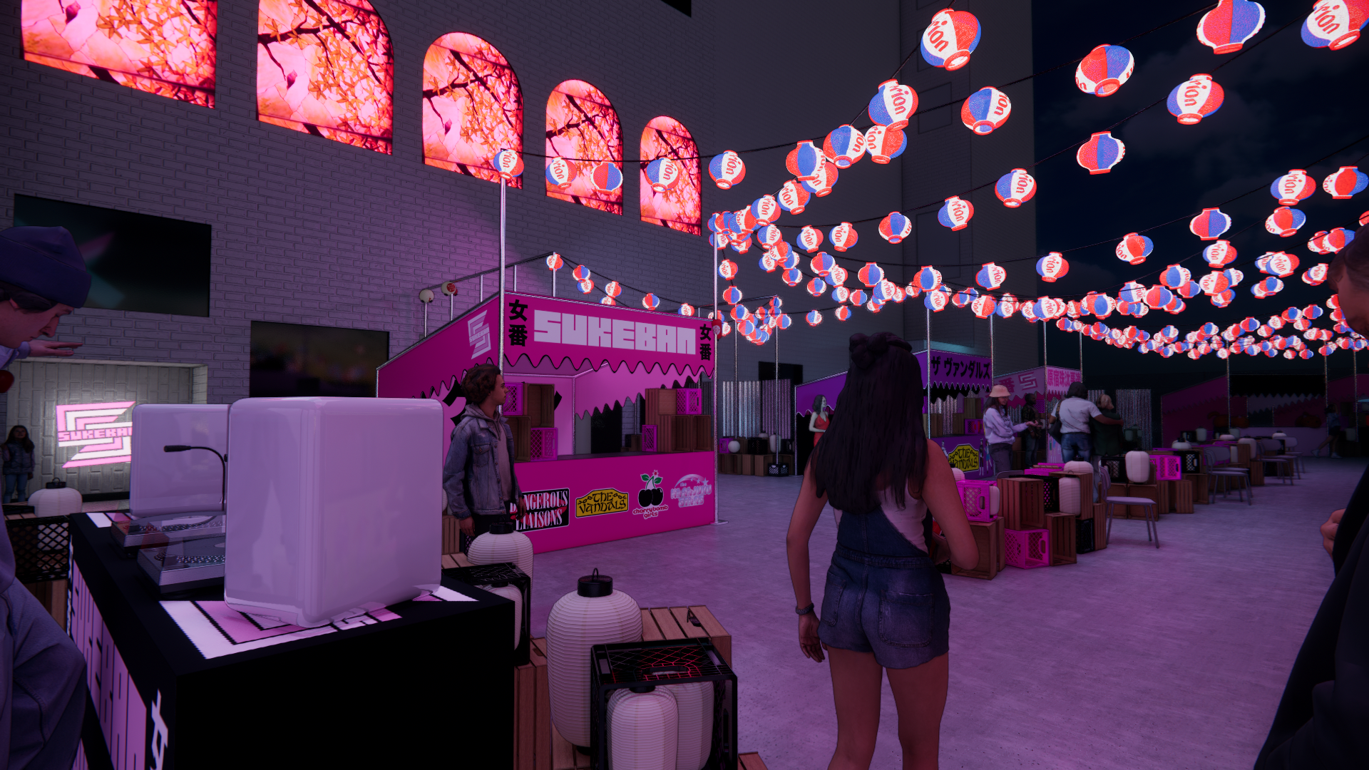 Night scene of an indoor festival or fair with hanging red, white, and blue lanterns and pink neon signs. People are walking around, and there are vendor booths with pink signage and wooden crates. The atmosphere is festive with colorful lighting.