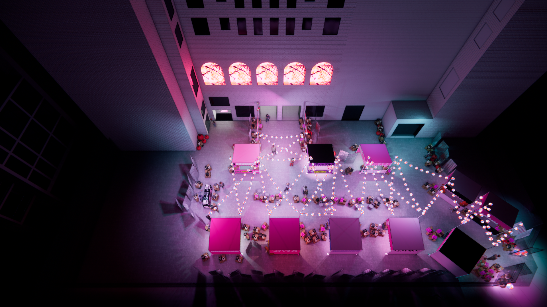 An overhead view of an outdoor event space decorated with pink and purple lights, string lights, and pink tents, set against a building with illuminated windows showing pink cherry blossom images.