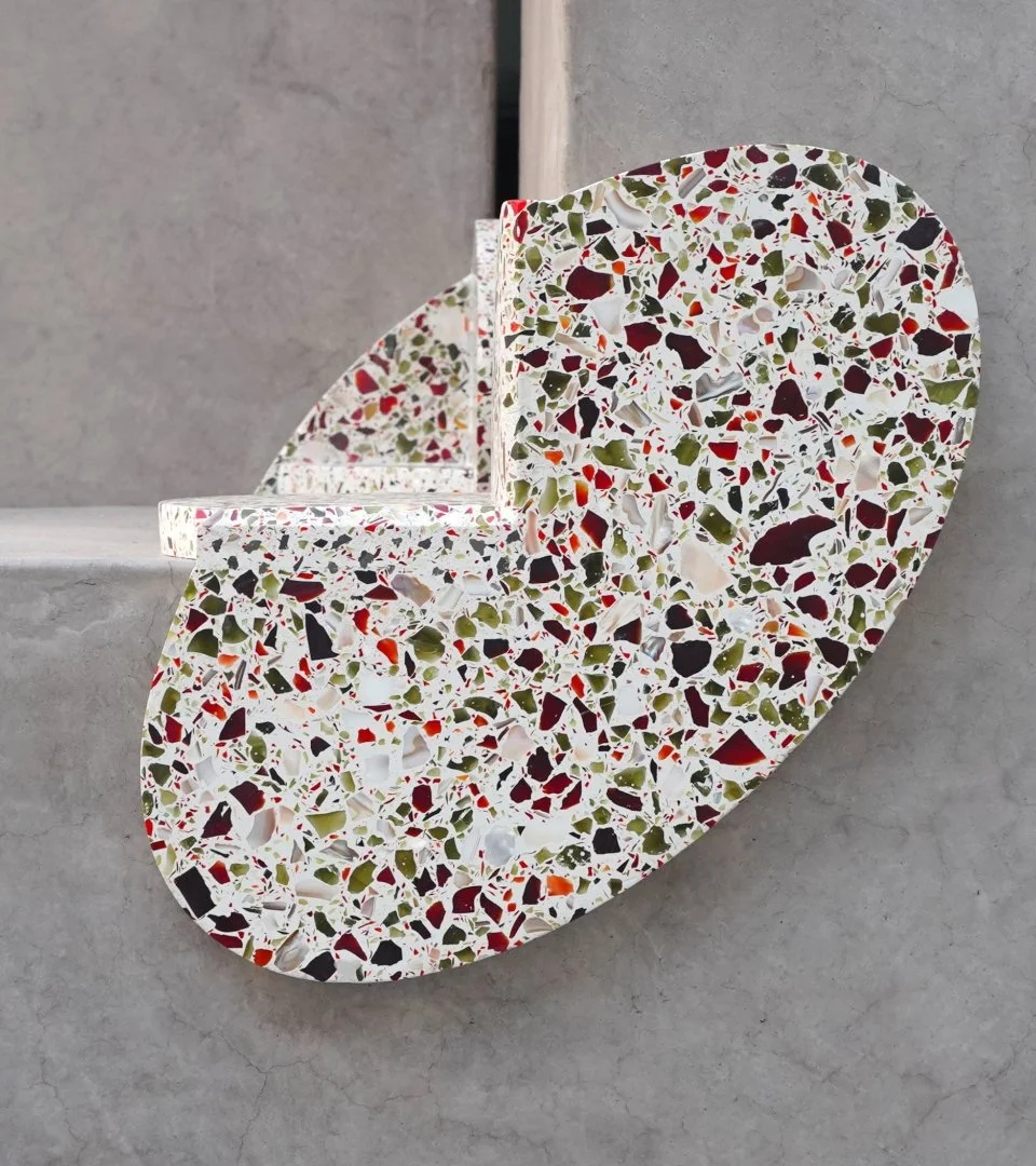 Development terrazzo-shaped dessert stand with a colorful terrazzo pattern, positioned on a concrete surface.