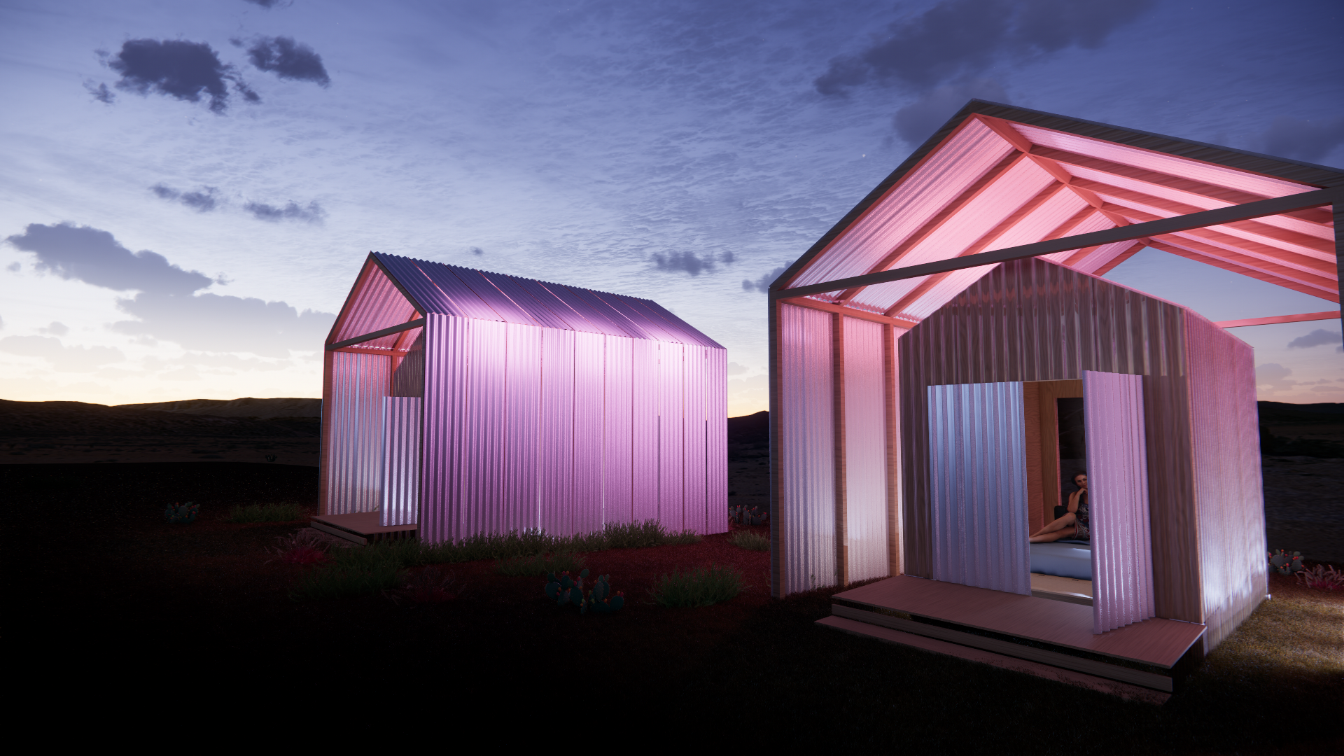 Two modern, illuminated structures with corrugated metal walls at sunset, one pink and the other purple, with a person sitting inside the pink structure.