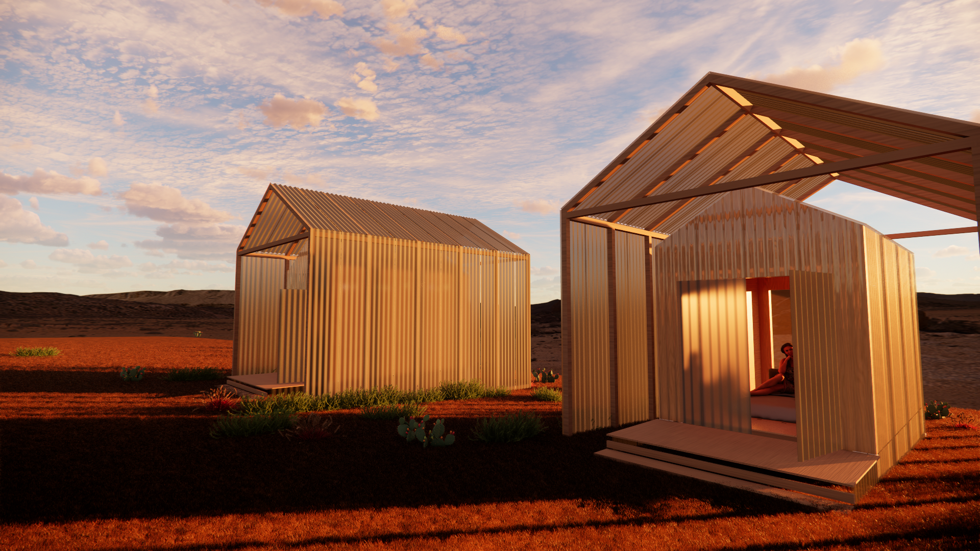 Two modern, minimalist structures with metal roofing and siding sit on a reddish desert landscape during sunset. One person is inside one of the structures, sitting with legs extended, in a relaxed pose.