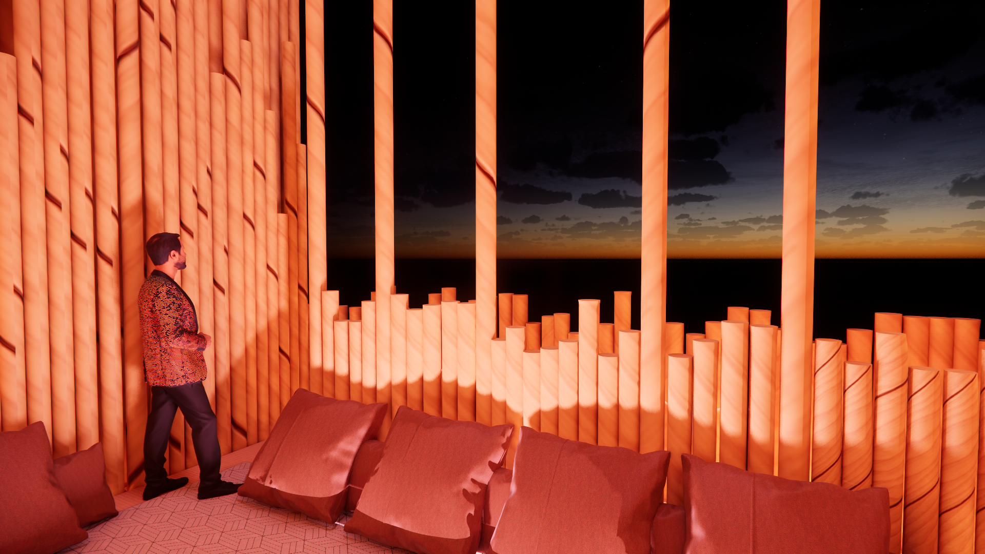 Man standing in a room with large illuminated orange pillar-like structures and a view of a sunset sky through large open windows.