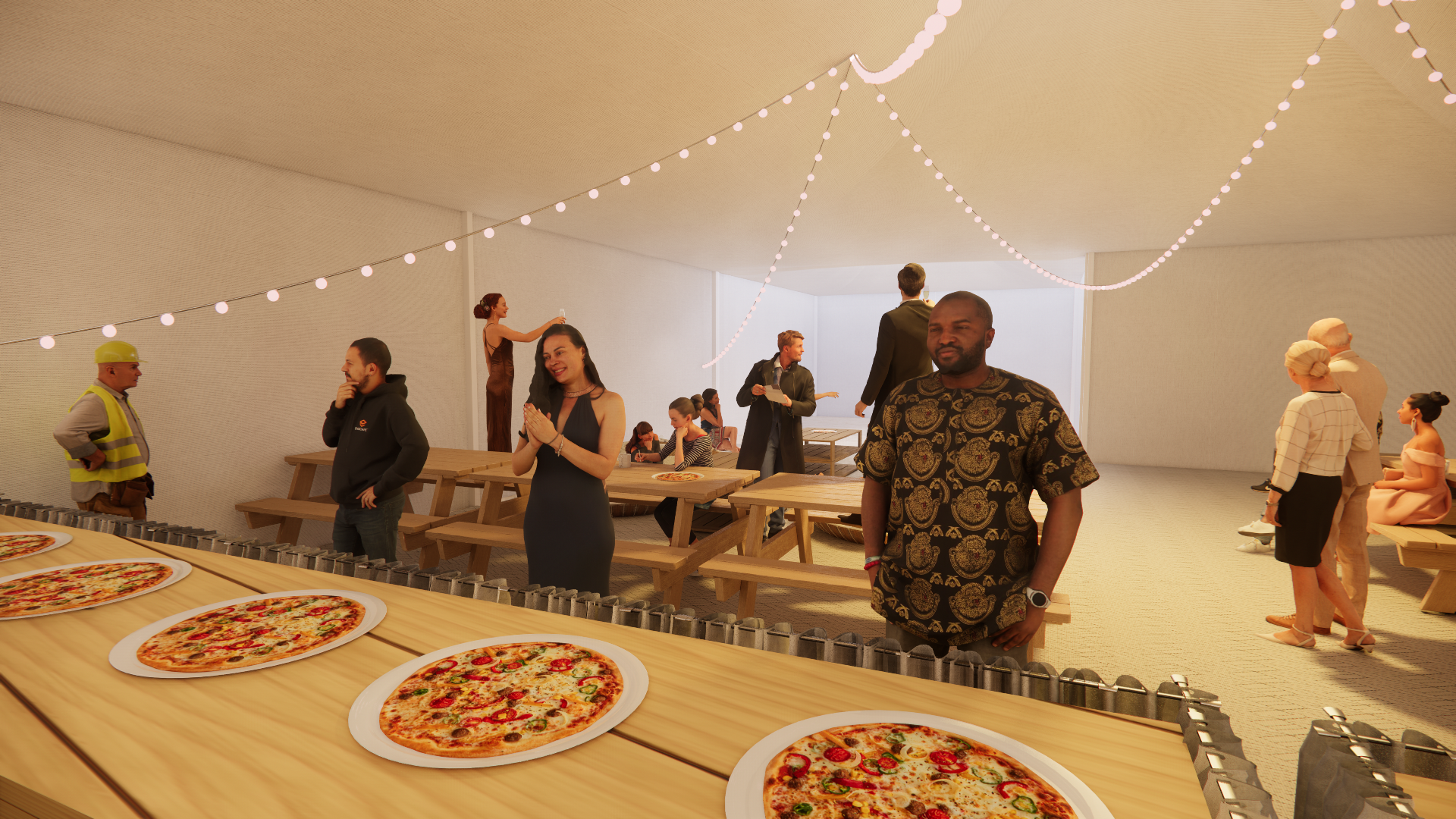 People gathered in a modern indoor space with string lights, some standing, some sitting at picnic tables, and several pizzas on display in the foreground.