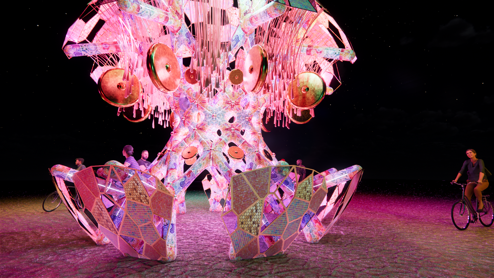 A colorful, illuminated sculpture resembling a butterfly or flower, set against a dark night sky with stars. There are people and cyclists nearby, observing and riding around the installation.