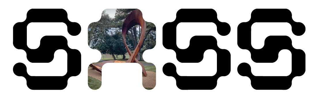 Photo of a large abstract outdoor sculpture in a park, surrounded by grass and trees.