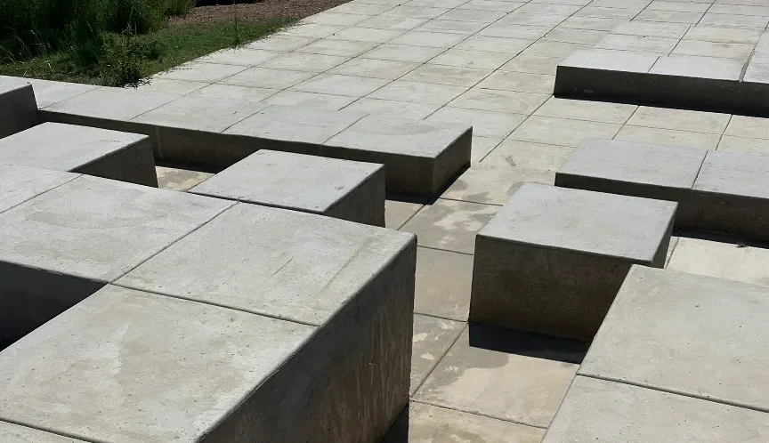 Concrete pavers arranged in a stepping pattern on an outdoor patio with greenery in the background.