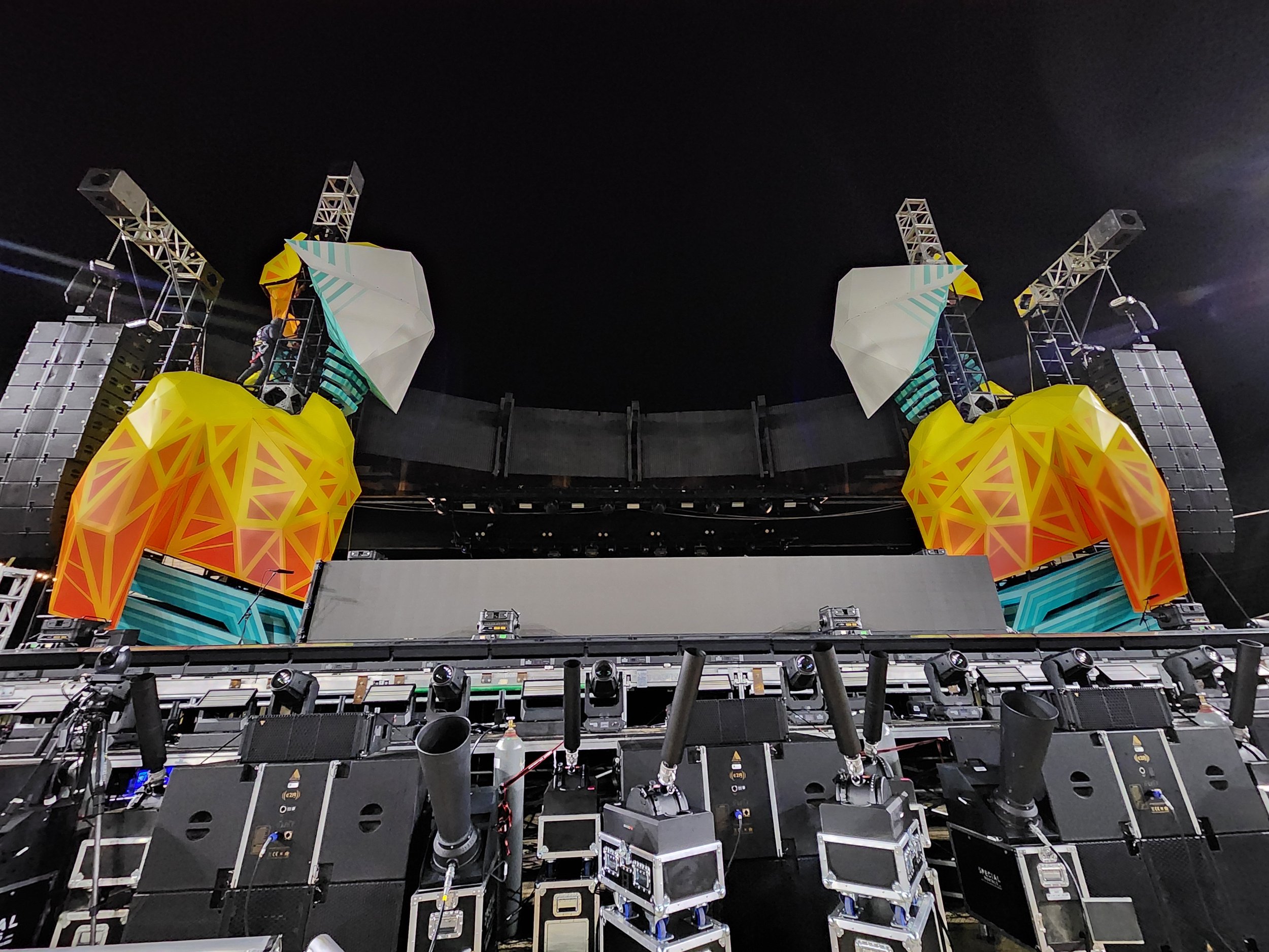 Stage setup with large speakers, lighting, and decorative structures resembling stylized pineapples at an indoor event or concert venue