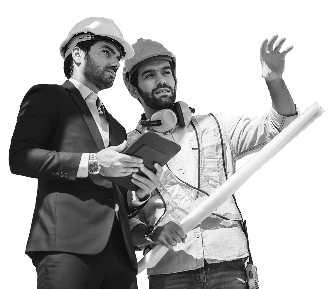 Two men, one in a business suit and the other in construction gear, wearing a helmet and ear protection, examining a set of blueprints.