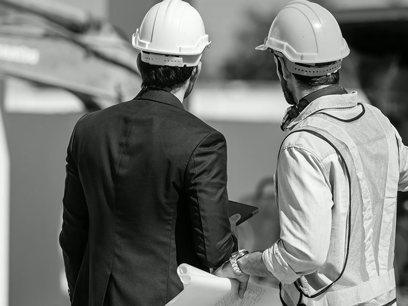 Two construction professionals in hard hats having a discussion at a construction site.