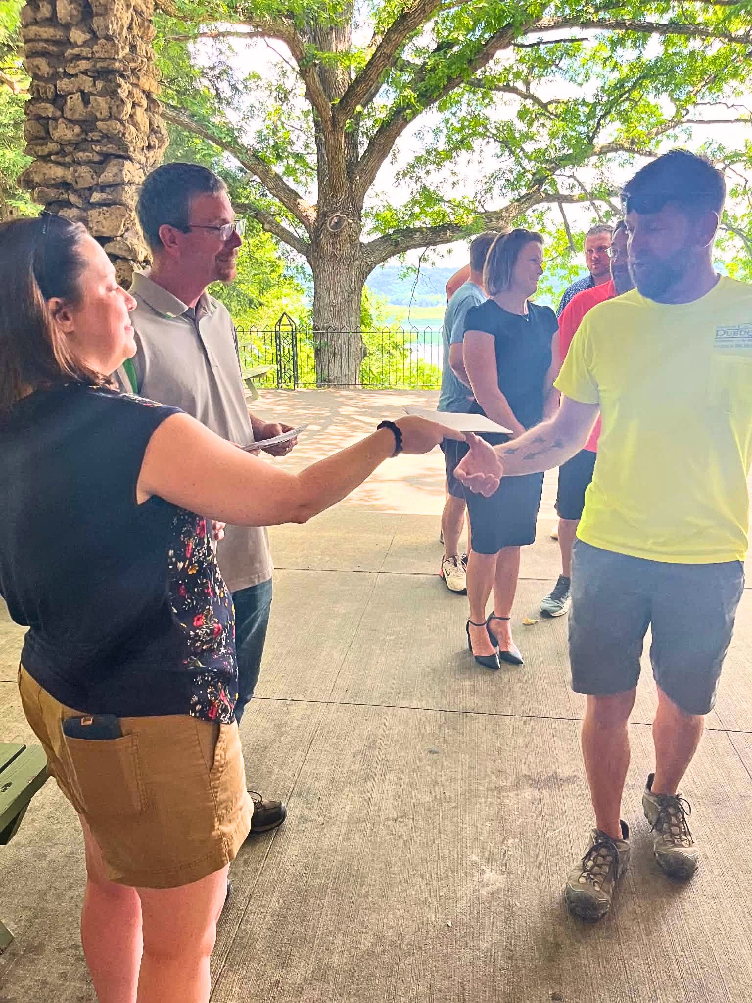Volunteer hands envelope to a parks maintenance worker at event