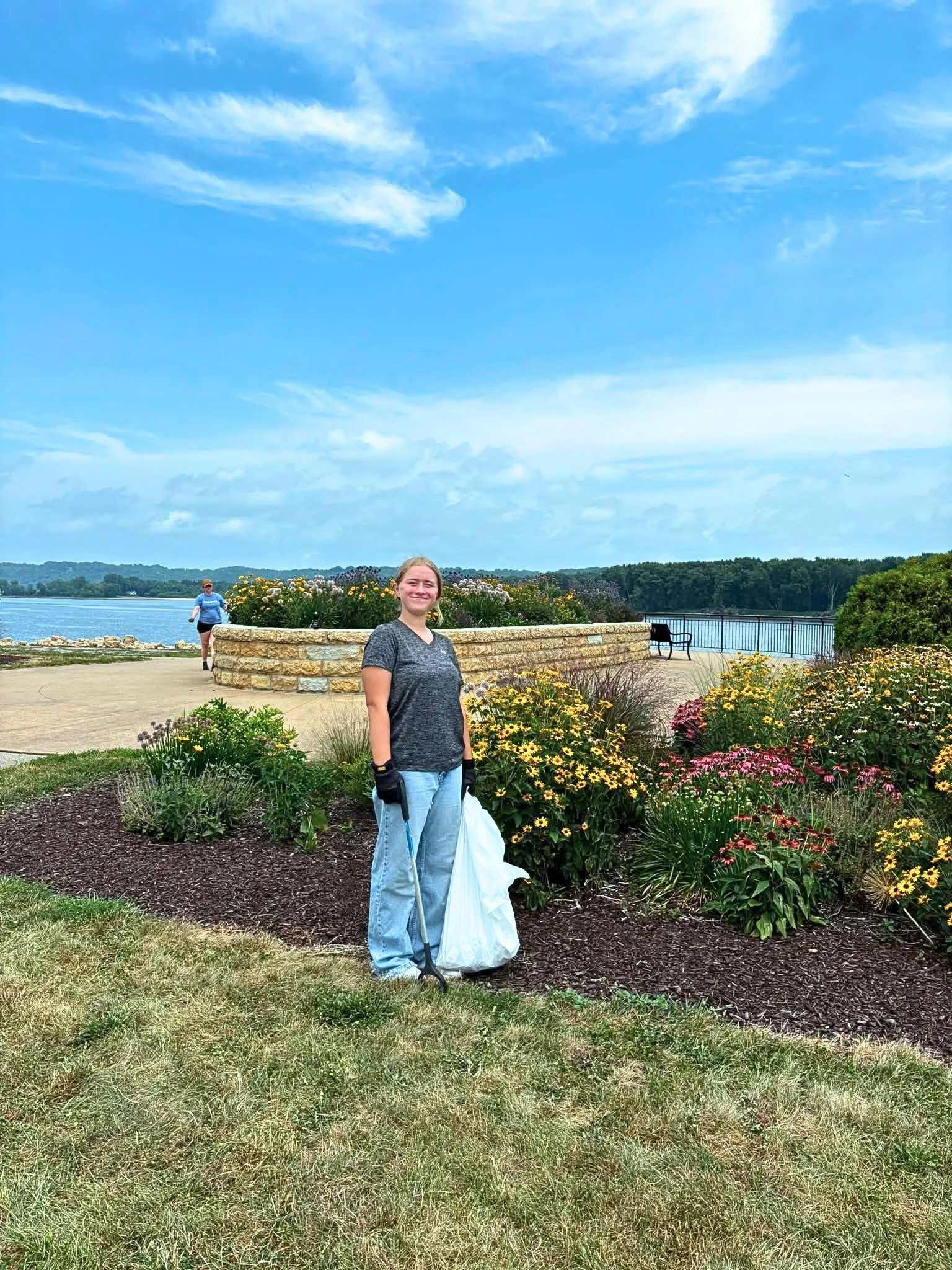 Volunteer with trash bag cleaning up AY McDonald Park in Dubuque, IA
