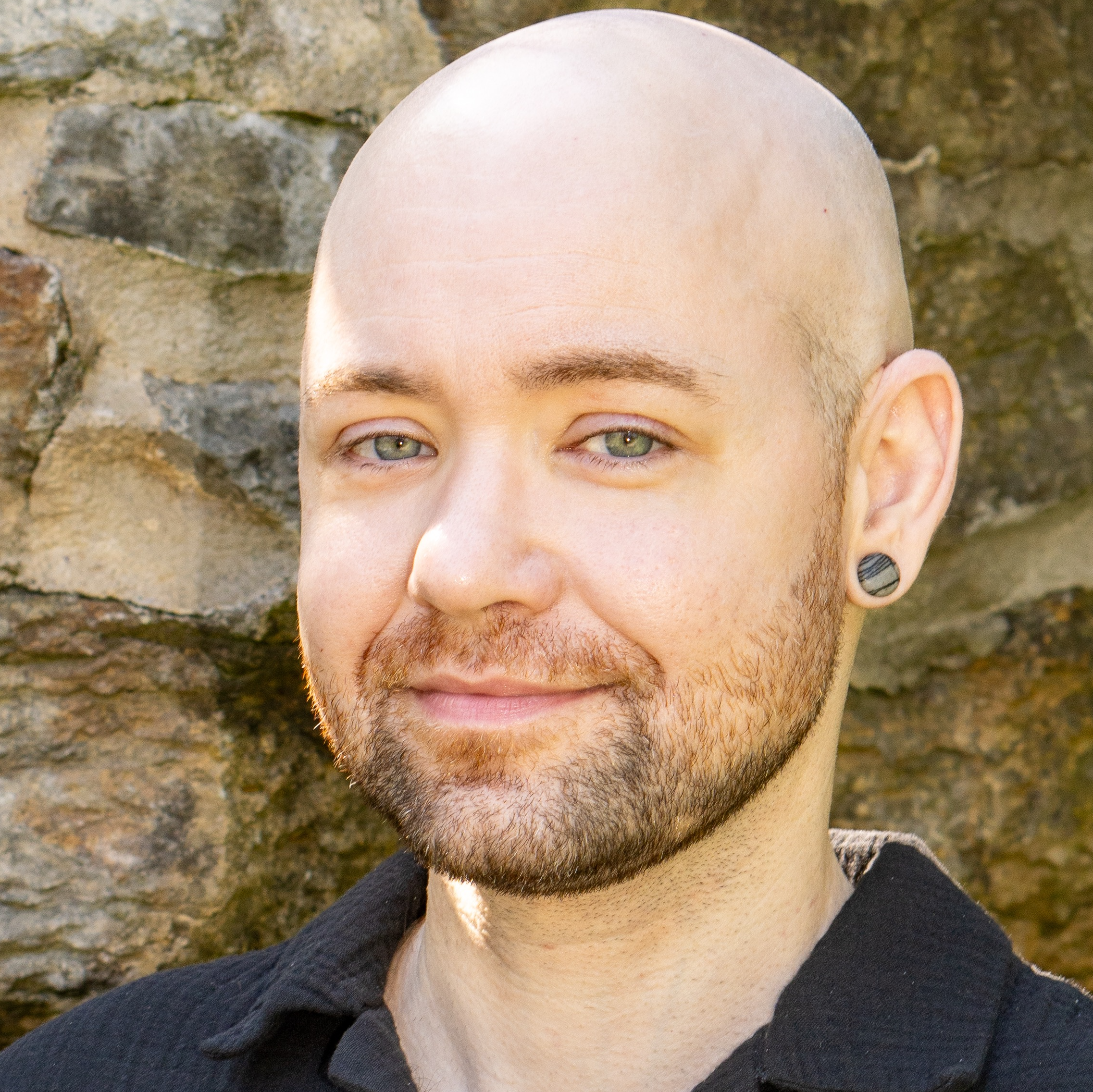 Augustin Kendall, a psychology book editor, standing in front of a stone wall
