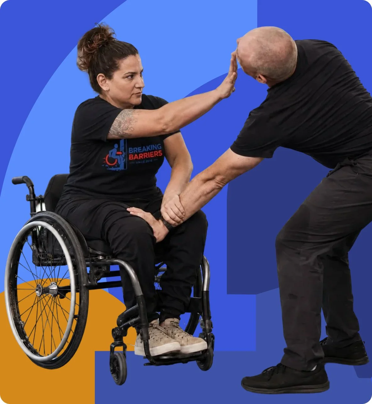 A wheelchair user practices a self-defense technique with an instructor