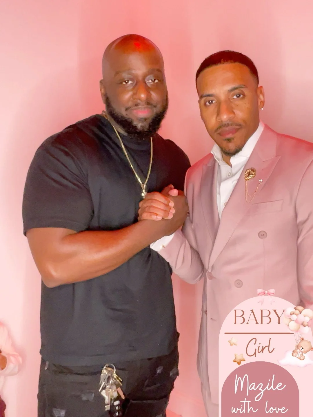 Two men shaking hands, one dressed in a black t-shirt and the other in a pink suit, with pink background and baby shower decoration reading "BABY Girl Mazile with love."