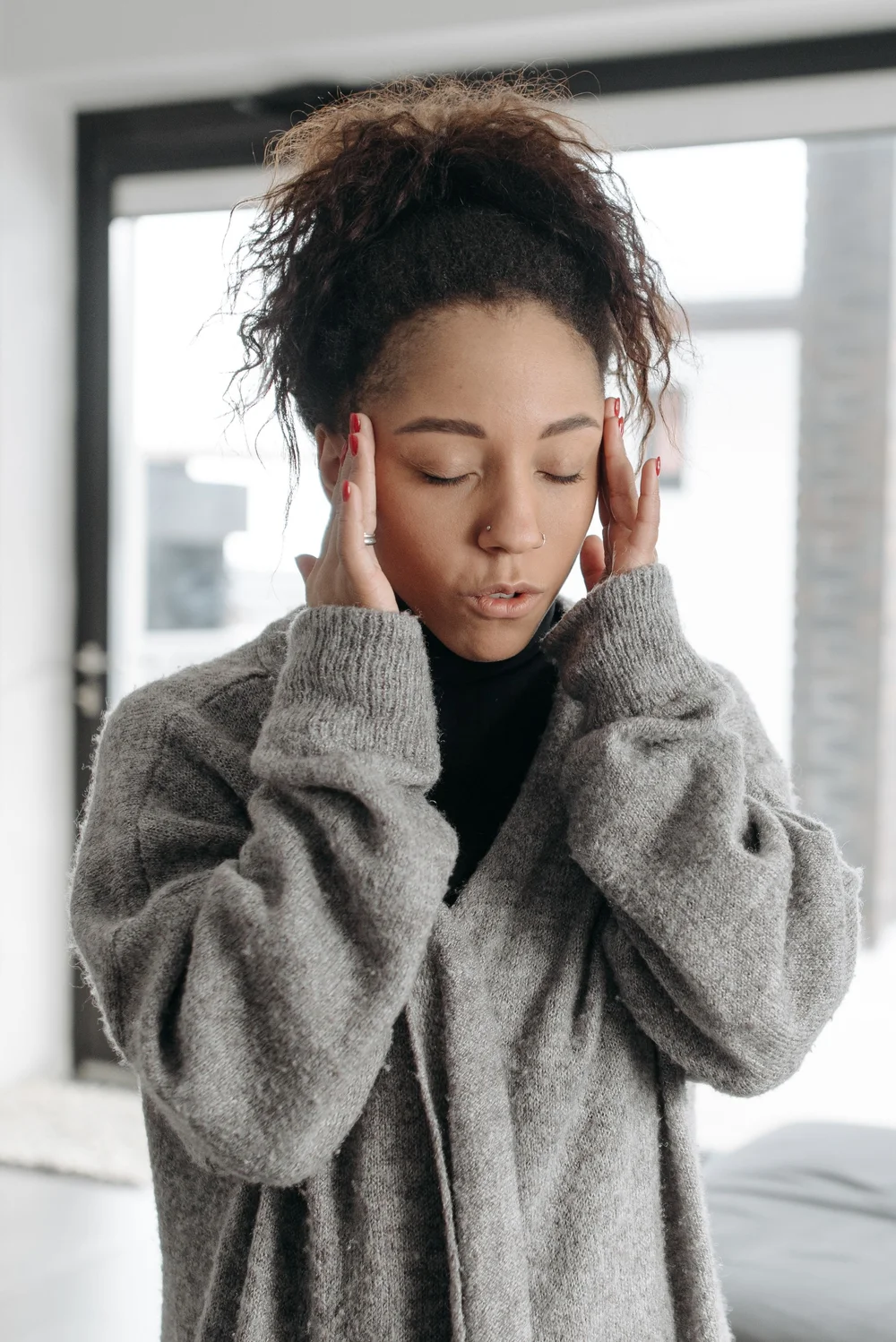 A woman in a gray sweater holding her head