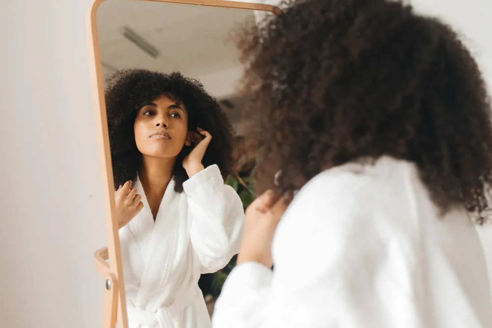 A woman looking at her reflection in a robe