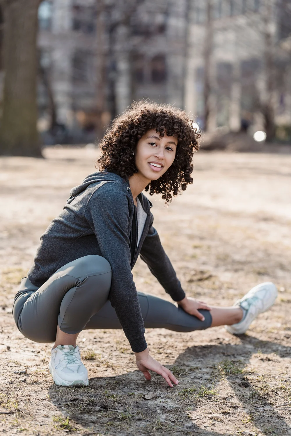 A woman crouching to stretch outdoors