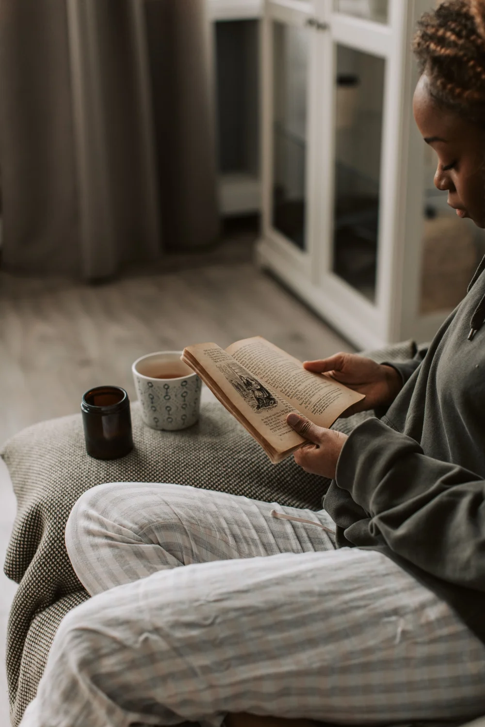 A woman reading an old book with tea