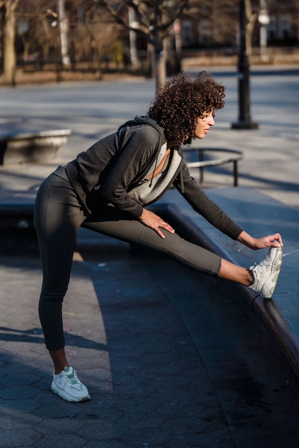 A woman stretching her leg on a park bench