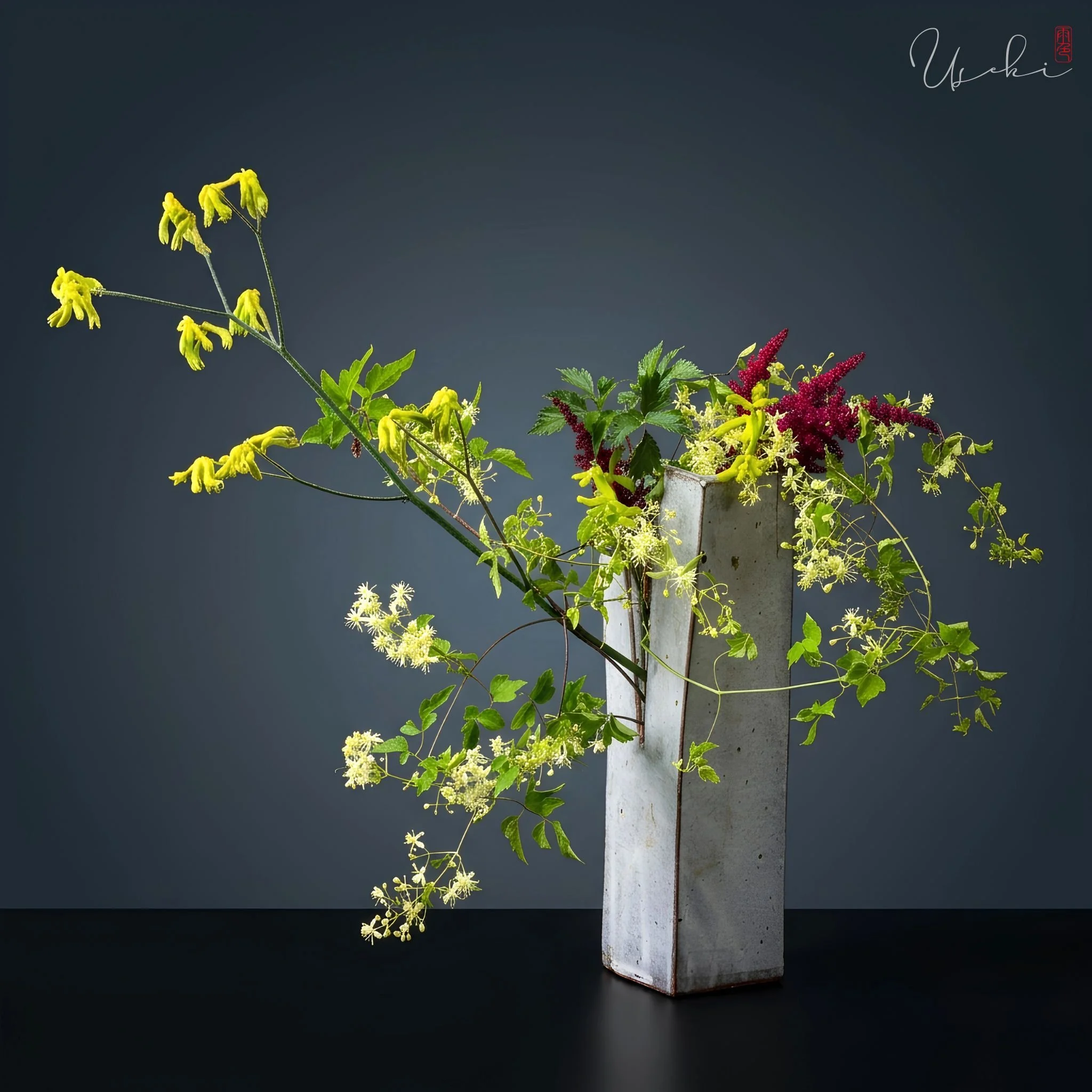 Sogetsu Ikebana slender yellow floral display using an architectural textured grey vase
