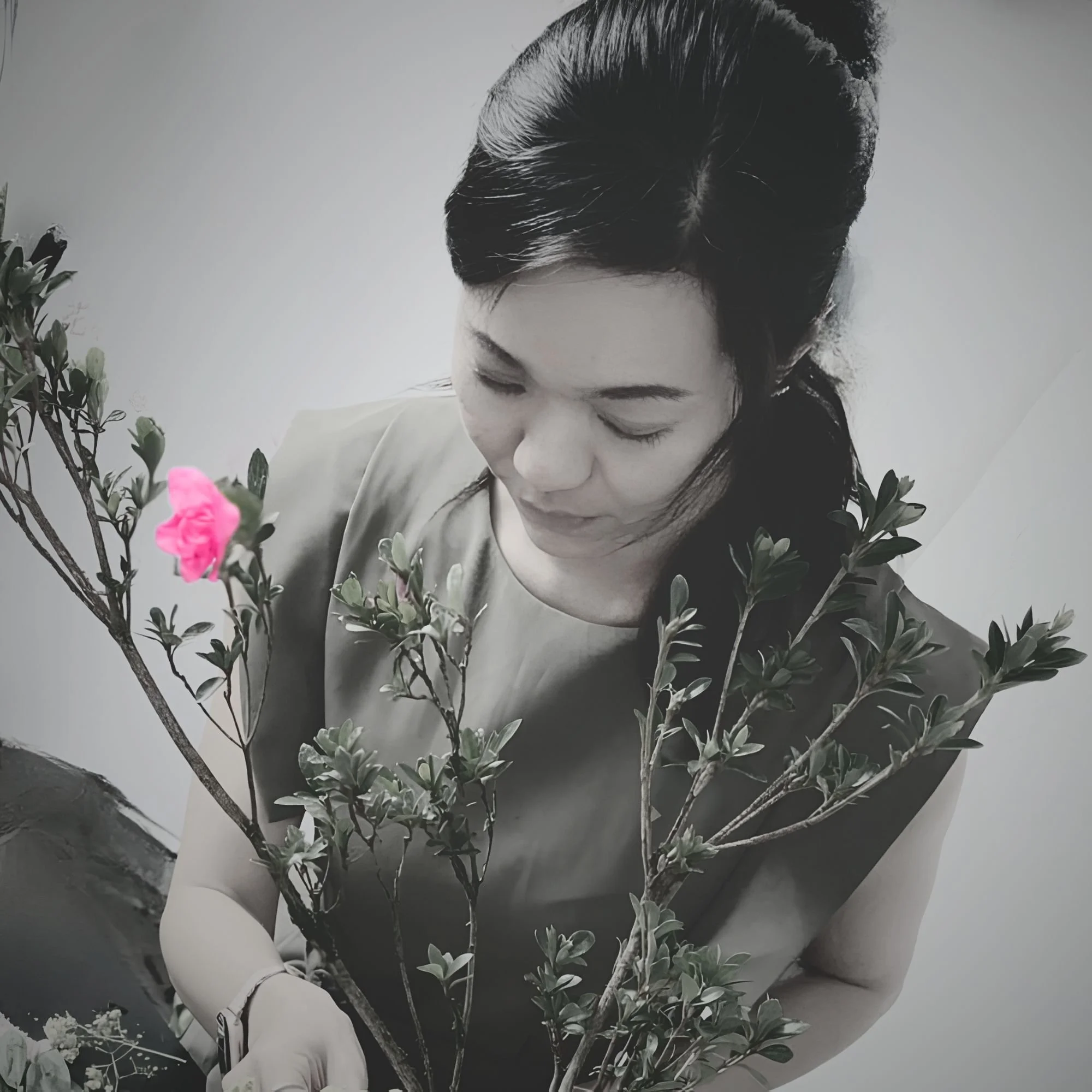 A candid black and white portrait of The Artist from USÉKI, deeply focused while creating a contemporary Sogetsu Ikebana flower arrangement in a minimalist studio setting.