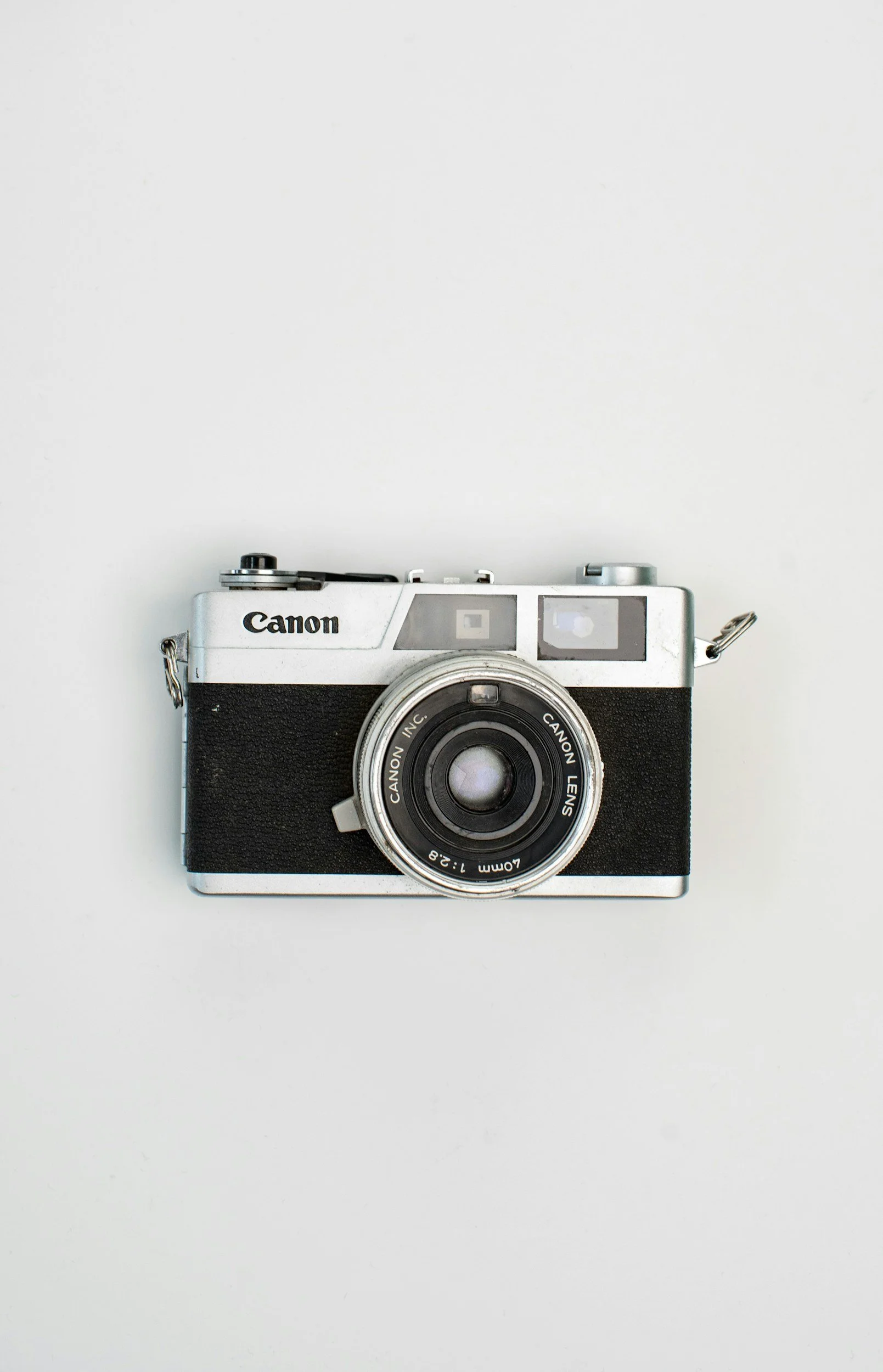 A vintage Canon film camera with a silver top and black body, placed against a plain white background.