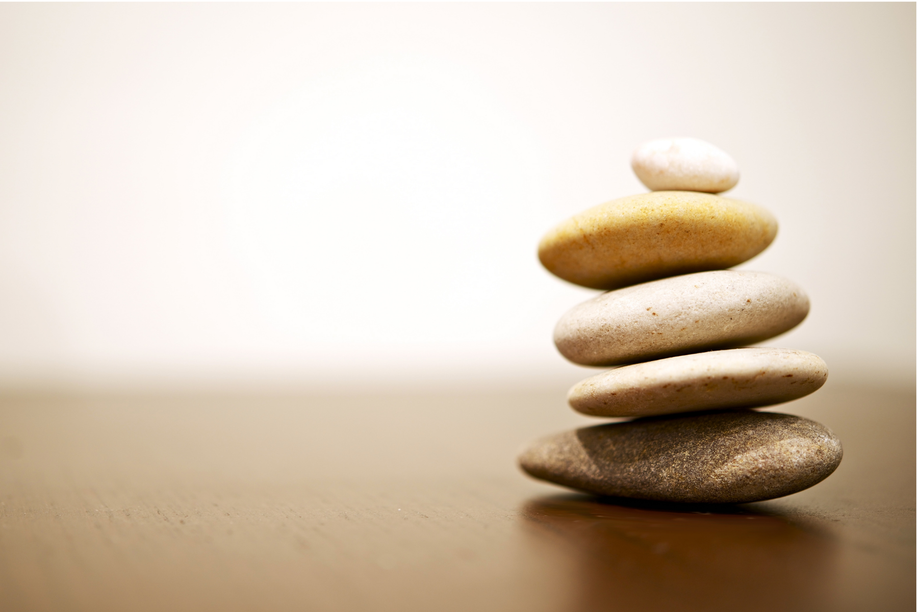 Stacked smooth stones on a wooden surface with a blurred neutral background.
