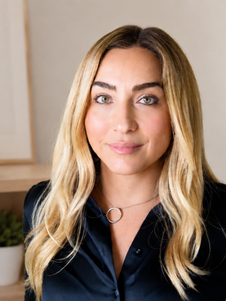 Mariana Enson therapist Hermosa Beach is smiling while looking at the camera, wearing a black satin blouse and a circular pendant necklace.
