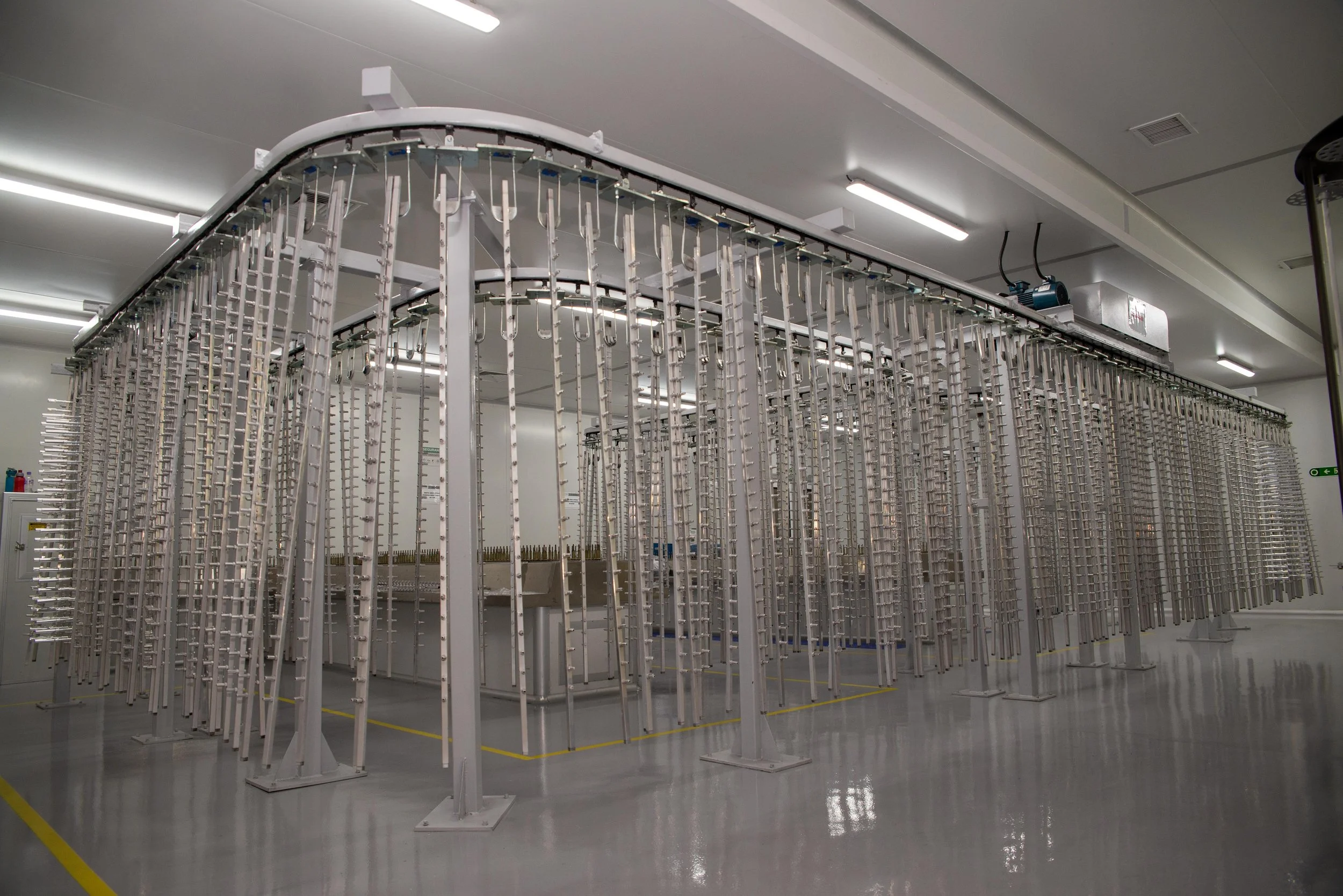Estrutura metálica no interior de uma instalação industrial da Thomriss Soluções em Embalagens, com iluminação artificial no teto de cor branca.