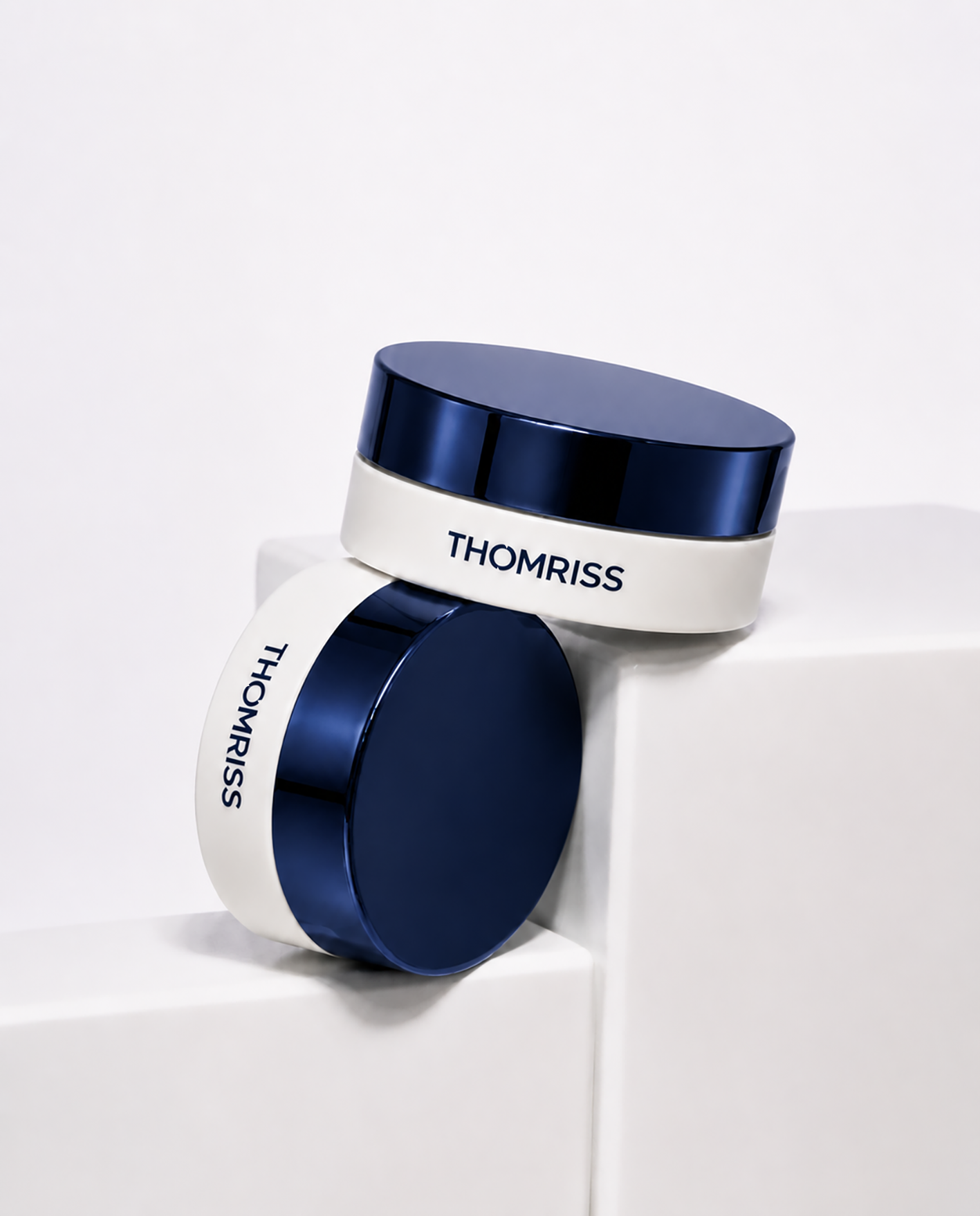 Imagem de dois rolos de fita adesiva, um branco com a marca 'THOMRISS' escrita em azul e um azul escuro, dispostos sobre uma superfície branca.